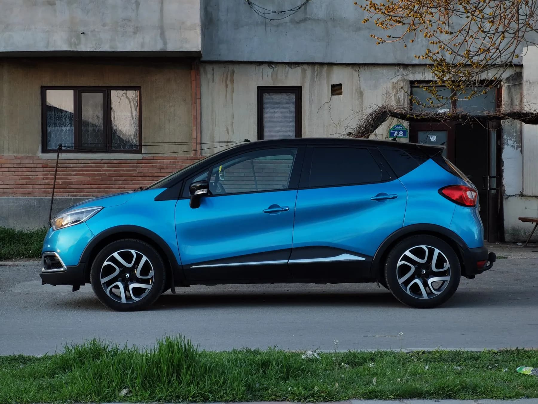 Renault Captur azul de perfil, delante de un edificio