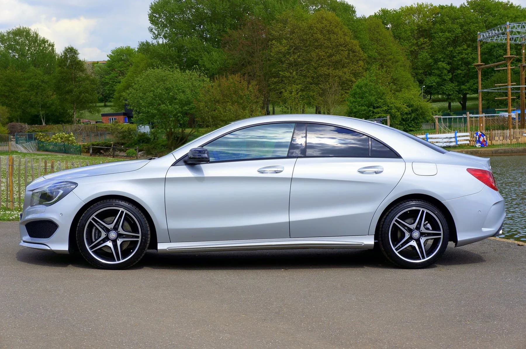 Mercedes-Benz CLA plateado de perfil, junto a un parque
