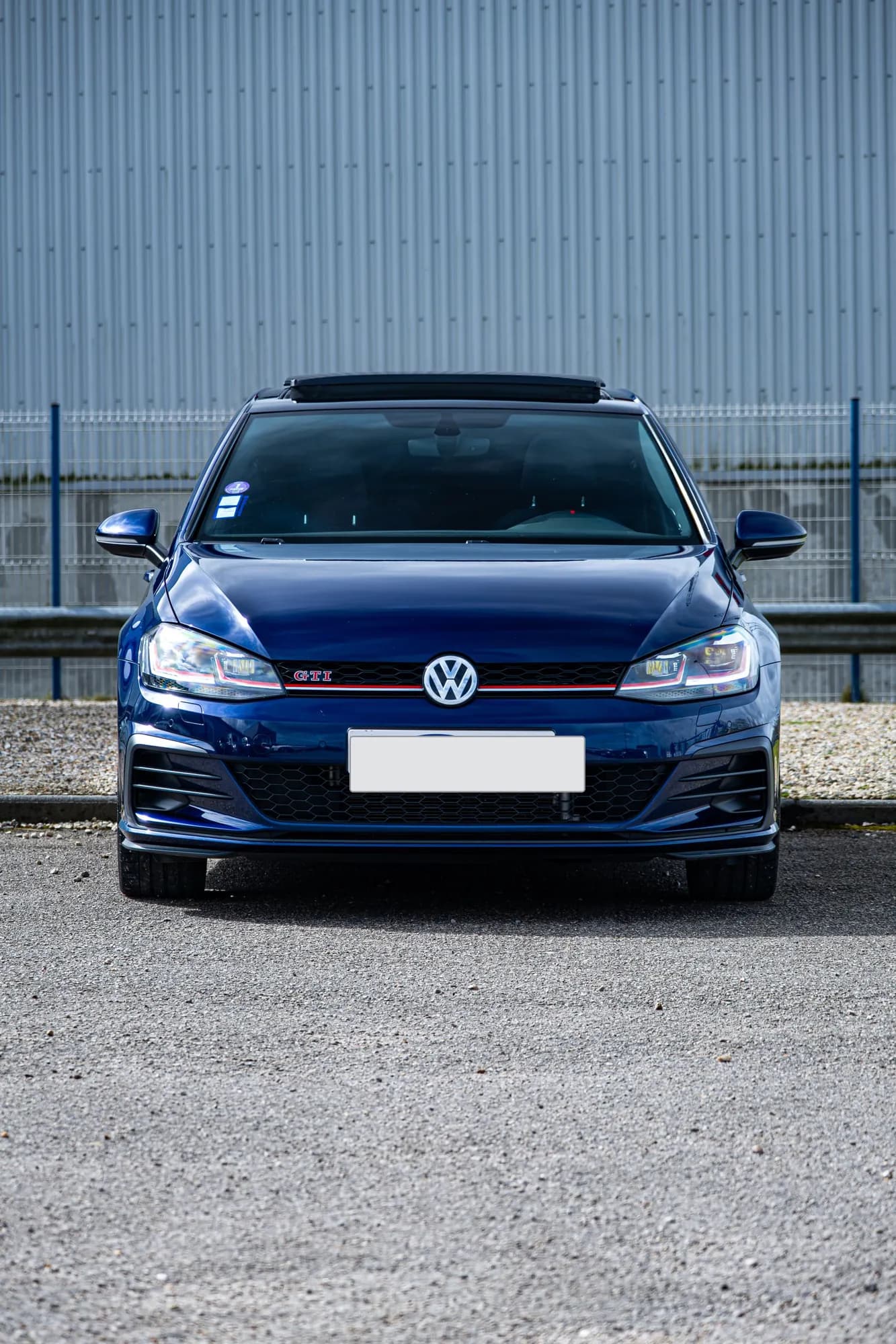 Volkswagen Golf GTI azul oscuro de frente, sobre grava
